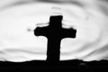 Gravestone cross reflected in rippling water