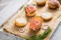 Gravlax a raw, marinated graved salmon with dill on bred roll bun with cream cheese, onion rings on tray with baking paper and