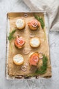 Gravlax a raw, marinated graved salmon with dill on bred roll bun with cream cheese, onion rings on tray with baking paper and