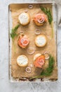 Gravlax a raw, marinated graved salmon with dill on bred roll bun with cream cheese, onion rings on tray with baking paper and