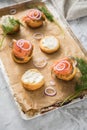 Gravlax a raw, marinated graved salmon with dill on bred roll bun with cream cheese, onion rings on tray with baking paper and