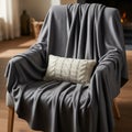 Gray armchair covered with a soft, draped gray blanket. A rectangular, cream-colored knitted pillow Royalty Free Stock Photo