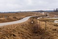 Wavy tarmac road framed with brown meadows. Royalty Free Stock Photo