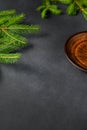 Gray Background with Live Christmas Tree Branches and Brown-orange Clay Plate. Christmas Theme Royalty Free Stock Photo