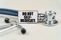 On a gray background, a stethoscope and a cardboard sign with the inscription - Do not self-medicate Royalty Free Stock Photo