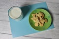 on a gray background there is a glass of milk and a green plate with lean cookies