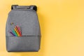 Gray backpack with autism infinity rainbow symbol sign, colored pencils in yellow background. Top view. World autism Royalty Free Stock Photo