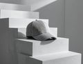 Gray Baseball Cap Resting On White Staircase Against White Background Royalty Free Stock Photo