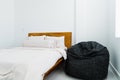 Gray bean bag inside bedroom next to comfy bed. Minimalist bedroom interior design. Royalty Free Stock Photo