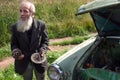 Gray-bearded elderly peasant farmer, outdated car repairs