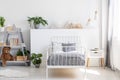 Gray bedding on a single bed with metal frame and a scandinavian style nightstand in a beautiful, bright kid bedroom interior with Royalty Free Stock Photo