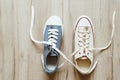 Gray and beige color casual new sneakers intertwined with white shoelaces on the wooden floor close up image. Love and friendship Royalty Free Stock Photo
