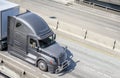 Gray big rig long haul semi truck transporting semi trailer with commercial cargo running on wide multiline highway Royalty Free Stock Photo