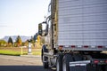 Gray big rig semi truck with refrigerator semi trailer turning on the parking lot for truck driver rest