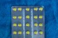 Gray blister with yellow pills on blue woolen background Royalty Free Stock Photo