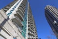 A gray and blue skyscraper and office buildings with metal balconies with tall black light posts and bare winter trees Royalty Free Stock Photo