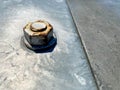 Gray bolt and rusty brown nut on a green metal wall Royalty Free Stock Photo