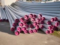 Gray bundled sewer pipes made of gray plastic with magenta colored lids.