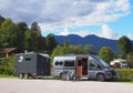 Gray camper van with a horse trailer in a parking lot