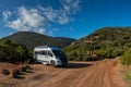 gray campervan parked on a dirt road in the green hills of Elba under a blue sky