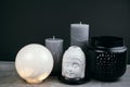 candles, round lamp and white ceramic Buddha head on a table opposite black wall Royalty Free Stock Photo