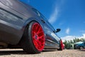 Gray car with lowered suspension and bright red forged wheels is on the parking. Against blue sky Royalty Free Stock Photo