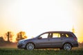 Gray car parked in countryside on orange clear sky at sunset background. Transportation, traveling, vehicles design concept