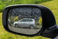 Gray car reflection in a wet rear view mirro