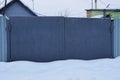 Gray closed metal gates in snowdrifts of white snow