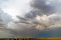 Gray cloudy sky and rain passing in the distance over an agricultural field. Royalty Free Stock Photo