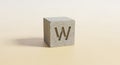 A gray concrete cube features the letter \