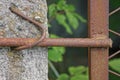 Gray concrete pole on a metal mesh fence with rusty brown rod Royalty Free Stock Photo