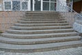 Gray concrete steps and iron railings at the sidewalk near the glass wall