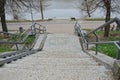 Gray concrete steps of the stairs and iron handrails in the park on the shore of the reservoir Royalty Free Stock Photo