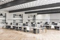 Gray concrete and wooden coworking office interior with multiple workplaces and bookcase shelves with books and folders. Royalty Free Stock Photo