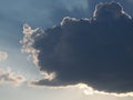 Gray cumulus on a blue sky covering the sun with sun rays coming out from behind the cloud Royalty Free Stock Photo