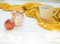 Gray cup of coffee over yellow coverlet and pumpkin on white wooden floor, romantic autumn interior closeup