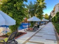 Gray deck chairs with an orange cushion by the pool with white umbrellas from the sun Royalty Free Stock Photo