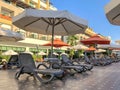 Gray deck chairs with an orange cushion by the pool with white umbrellas from the sun Royalty Free Stock Photo