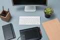 The gray desk with laptop, notepad with blank sheet, pot of flower, stylus and tablet for retouching Royalty Free Stock Photo