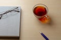 Gray diary, cup of tea, blue pen and glasses on a brown table, selective focus Royalty Free Stock Photo