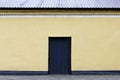 gray door, a wall with beige plaster, a roof, paving slabs