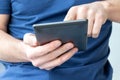 Gray e-reader electronic book in male hands. A man in a blue t-shirt with a tablet