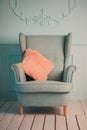 Gray easy armchair with pink scarf, pillow and book next to bed