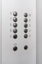 Gray elevator panel with silver buttons in a ten-story building