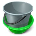 Gray empty plastic bucket with black handle in green basin. Royalty Free Stock Photo