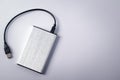 Gray external hard disk with black USB cable on white background Royalty Free Stock Photo