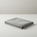 Gray fabric neatly folded in a rectangular shape on a clean, white surface. The fabric Royalty Free Stock Photo