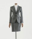 Gray female formal suit made up of jacket and skirt on a mannequin.