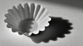 Gray fluted coffee filter casting shadow on textured surface Royalty Free Stock Photo